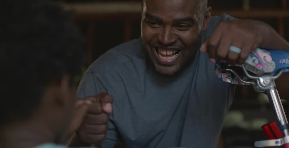 Smiling father fist bumps his child while looking over bicycle