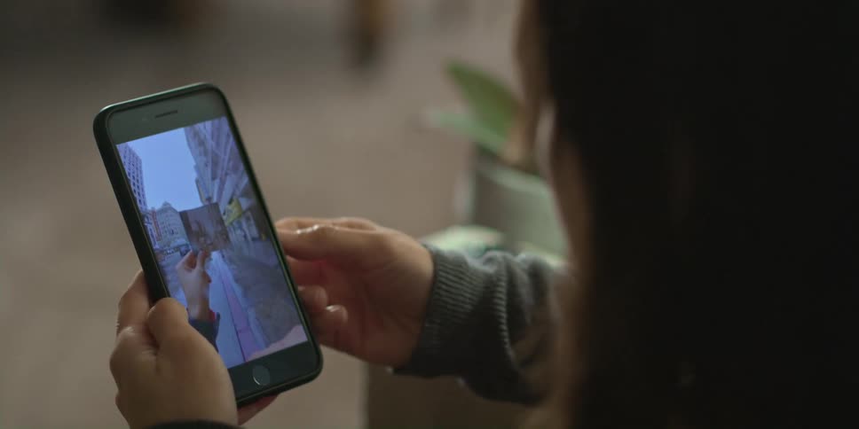 A woman views a photograph on a smartphone while indoors