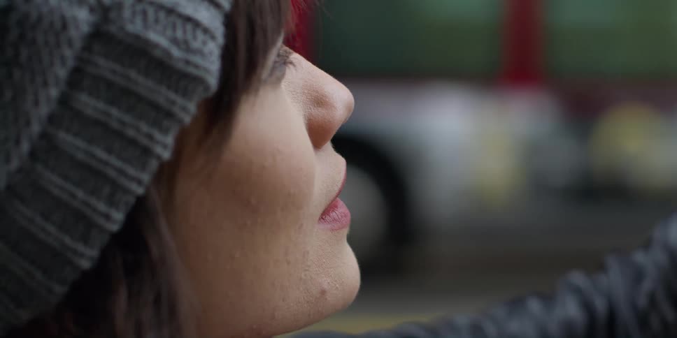 Woman standing examining site smiles as bus passes in the background