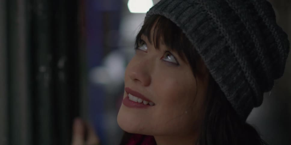 A woman walks through a city and looks up at the buildings and smiles