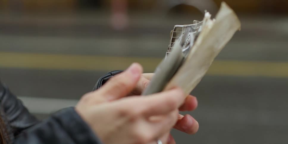 Woman with black leather jacket and ring looks at old photographs in the street