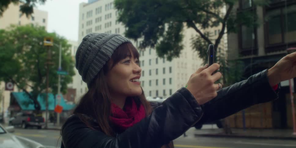 A woman is taking photos with her cellphone in a downtown city