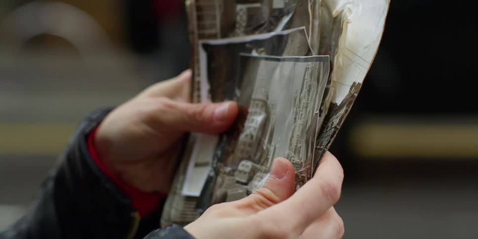 A person holds photos as cars drive by