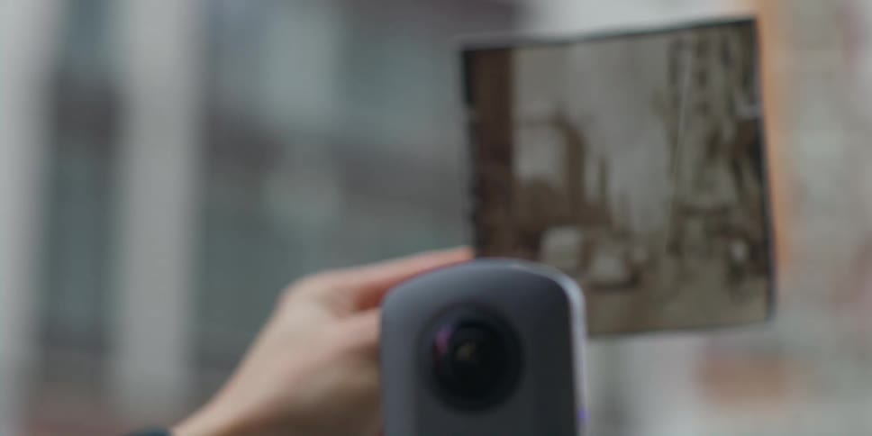 A person showing an old photo to a camera