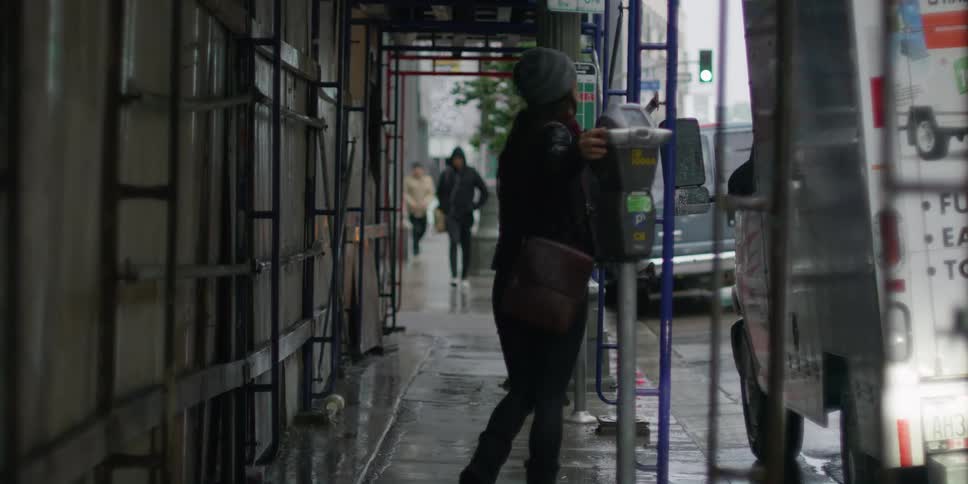 Woman walks along sidewalk past construction site and street