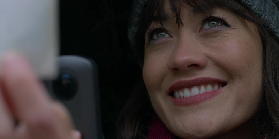 A woman smiles as she takes a photo of a picture