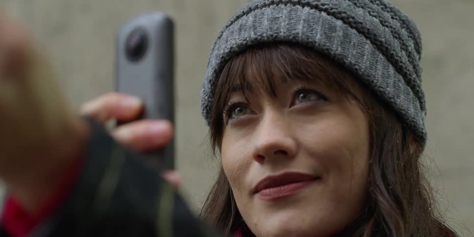 A woman is standing outdoors with her cellphone