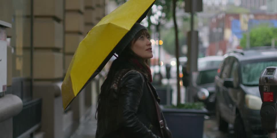 A woman is walking in the rain holding a yellow umbrella