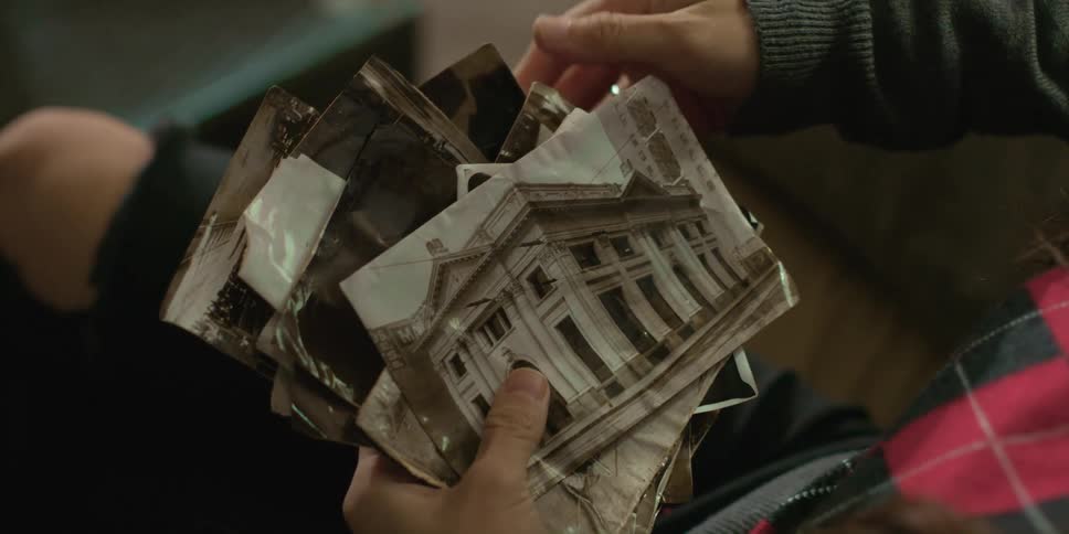A woman is sitting down looking at old photographs