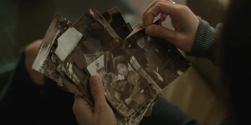 Woman with black ripped jeans looks down at old photographs