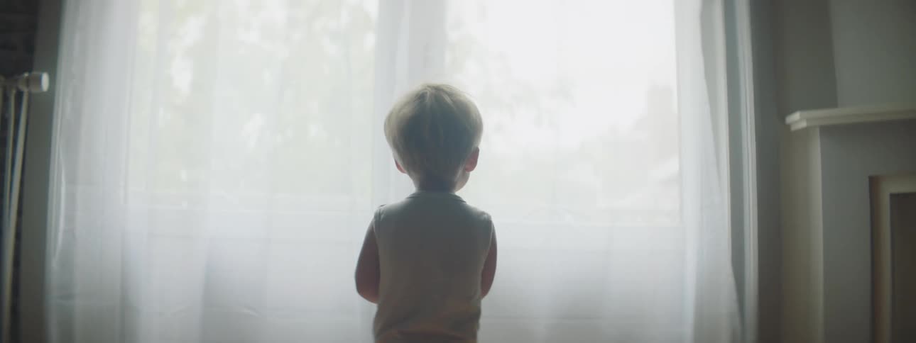 Toddler walking up to a window to look outside