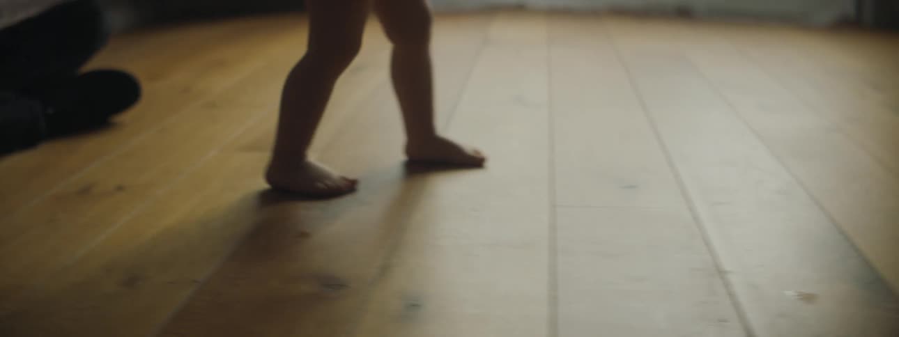 Toddler girls legs walking on the floor are silhouetted against the windows