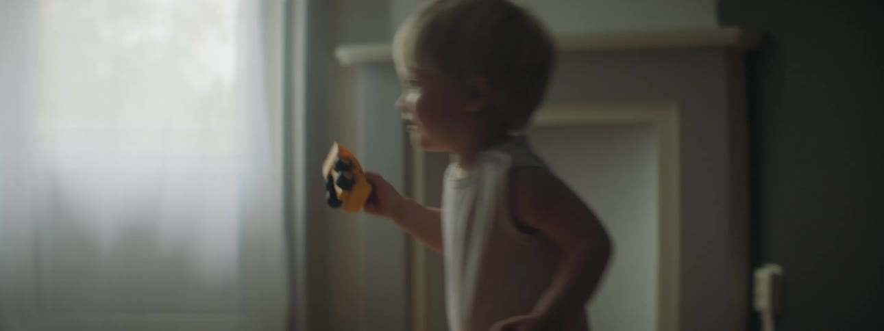 A young toddlers leans over and picks up a toy then begins to play