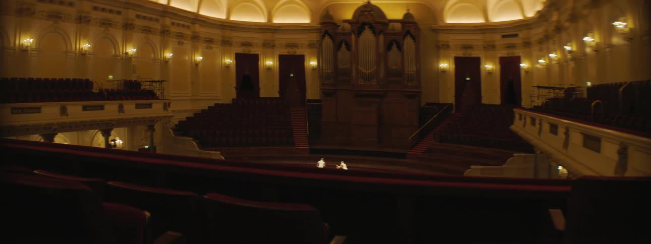 Two women with white dresses dancing in an auditorium