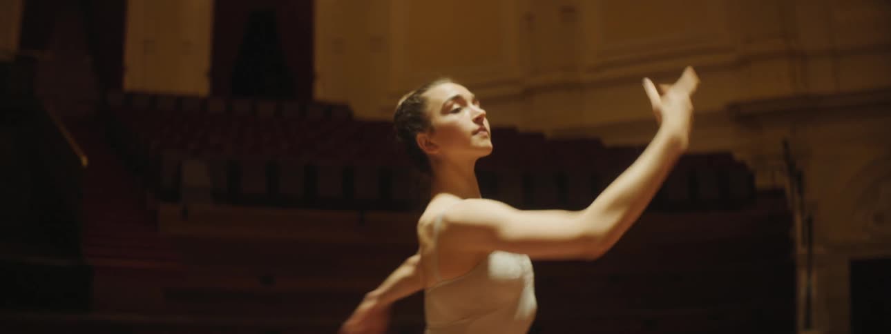 Two dancers dance on stage under dimly lit theater