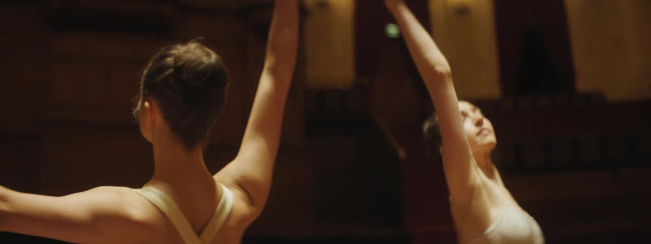 Two dancers dance a routine in wood paneled room