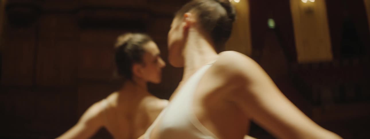 Two female ballet dancers move in a circle on stage