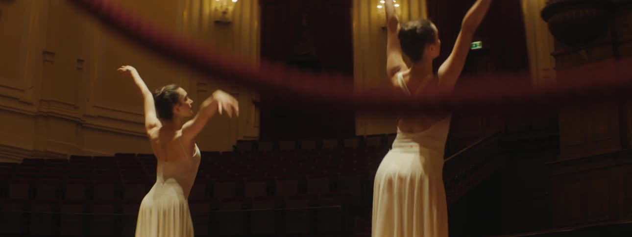 Two ballerina dance on point on stage