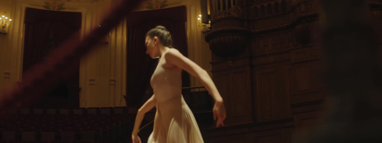 Two female ballerinas dance on a theater stage