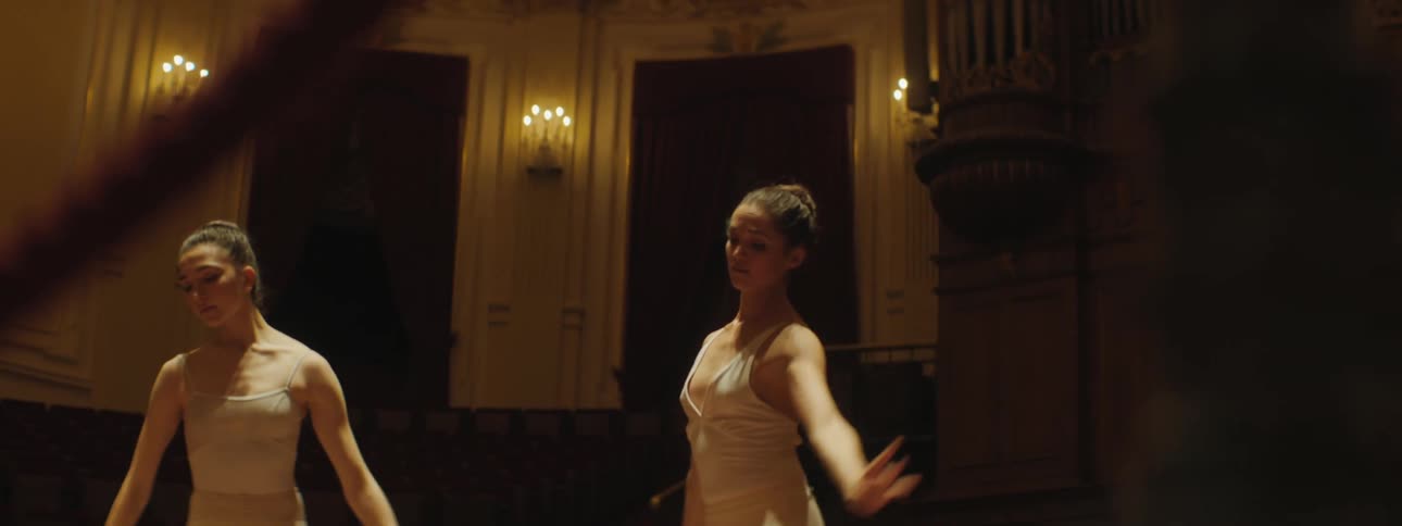 Two ballerinas dancing on a stage in an auditorium