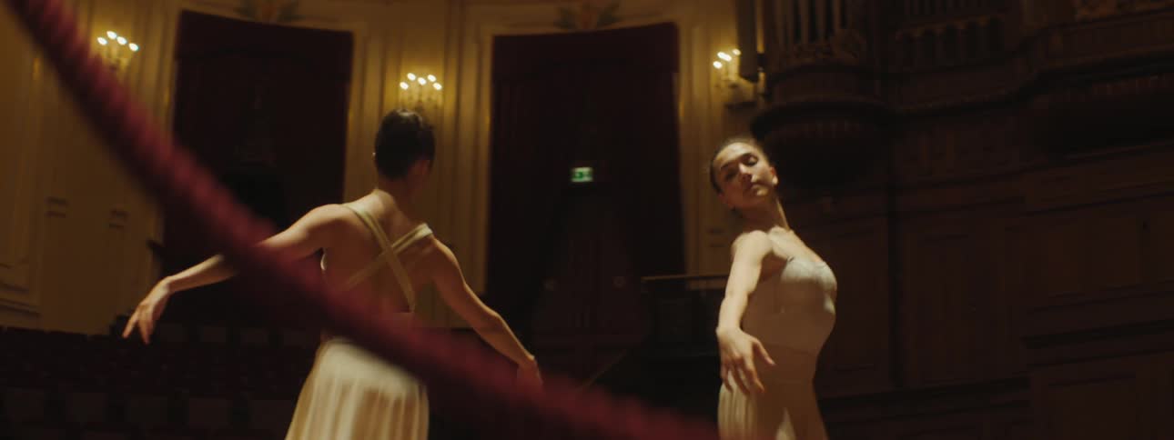 Two female ballet dancers practice on a stage in a theater