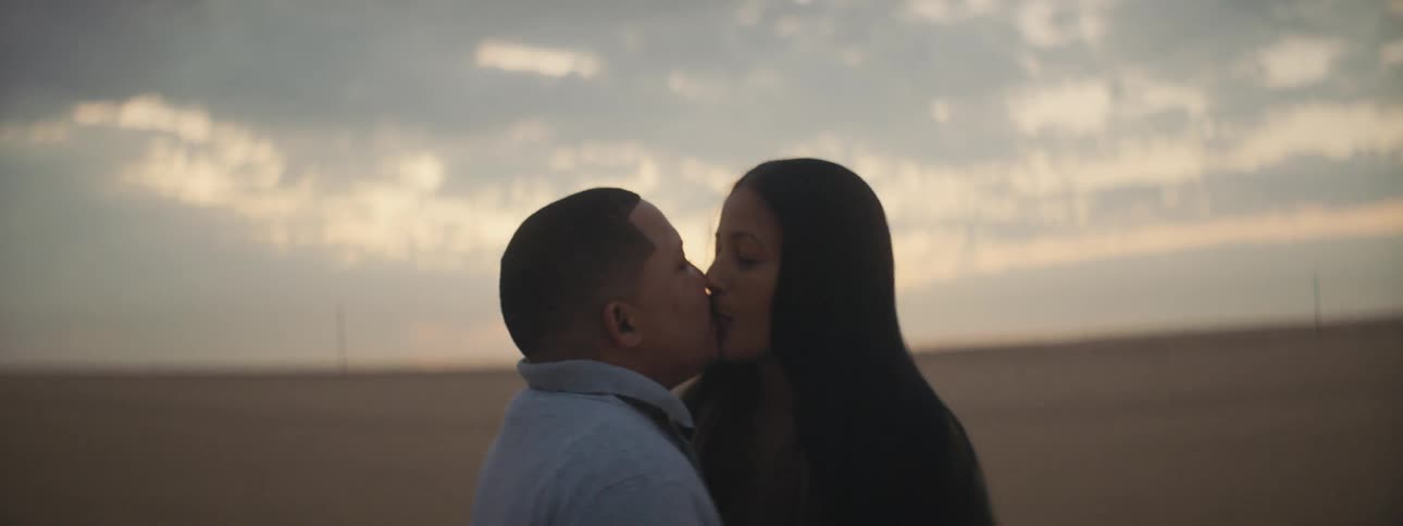 Man and woman kissing each other are silhouetted against the sunset