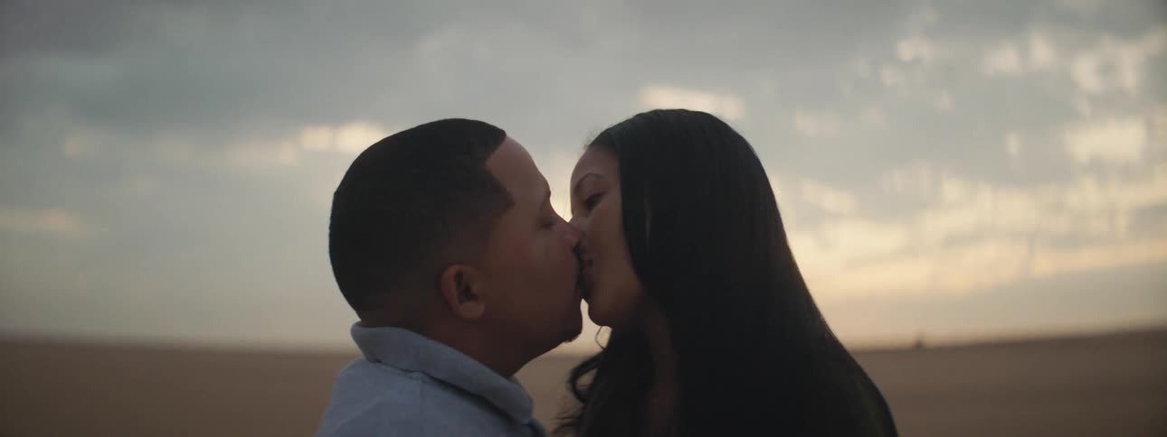 Man and woman lovingly kiss and looking into each others eyes on the plain at dusk