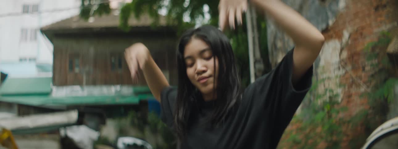 A girl dancing with buildings plants the sky and clouds in the background