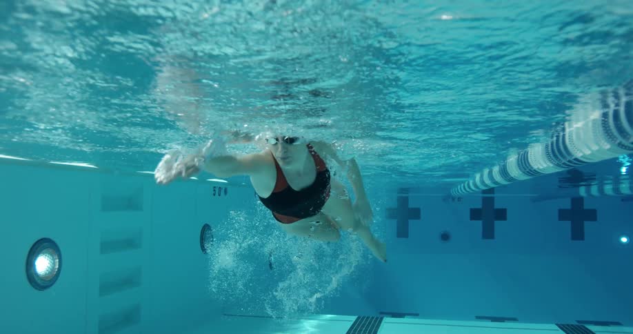 A woman is swimming with goggles in a pool