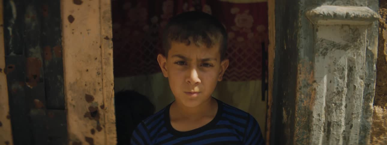 A young boy standing in a doorway in a village