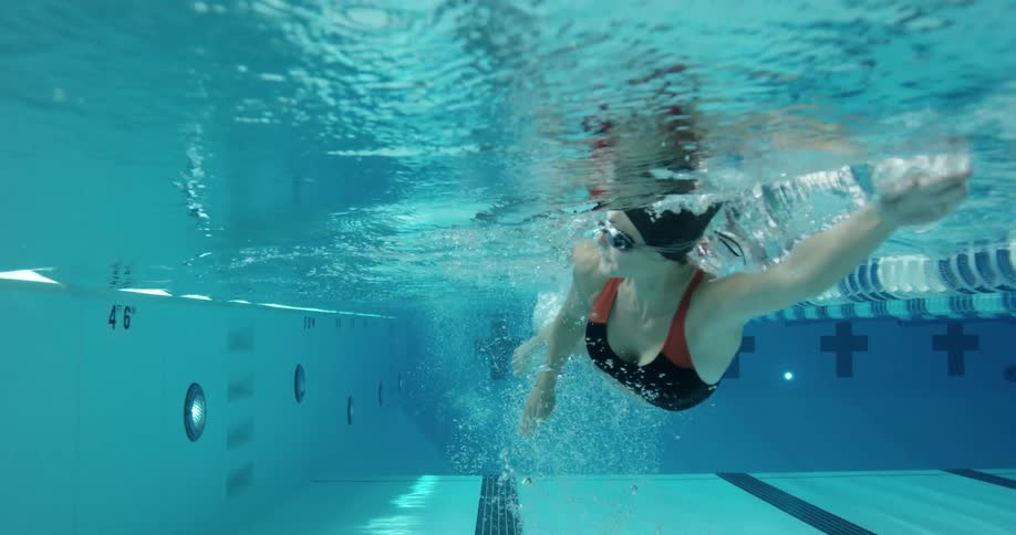 A woman who is seen from beneath the water, swims in a lane in a pool