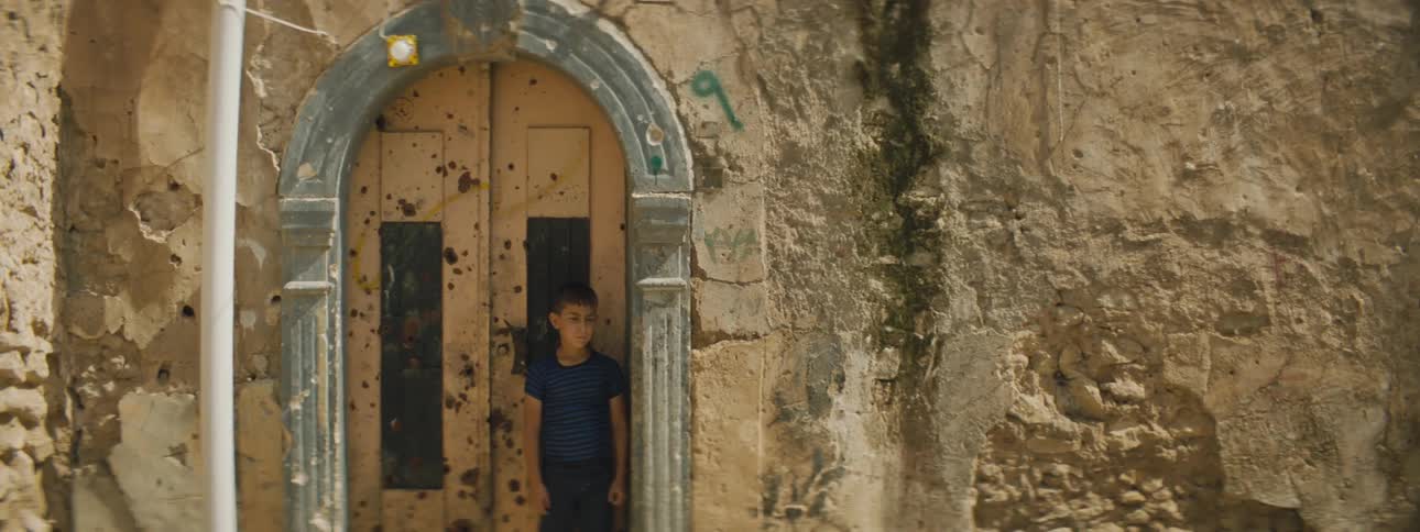 A young boy stands in the doorway of a building