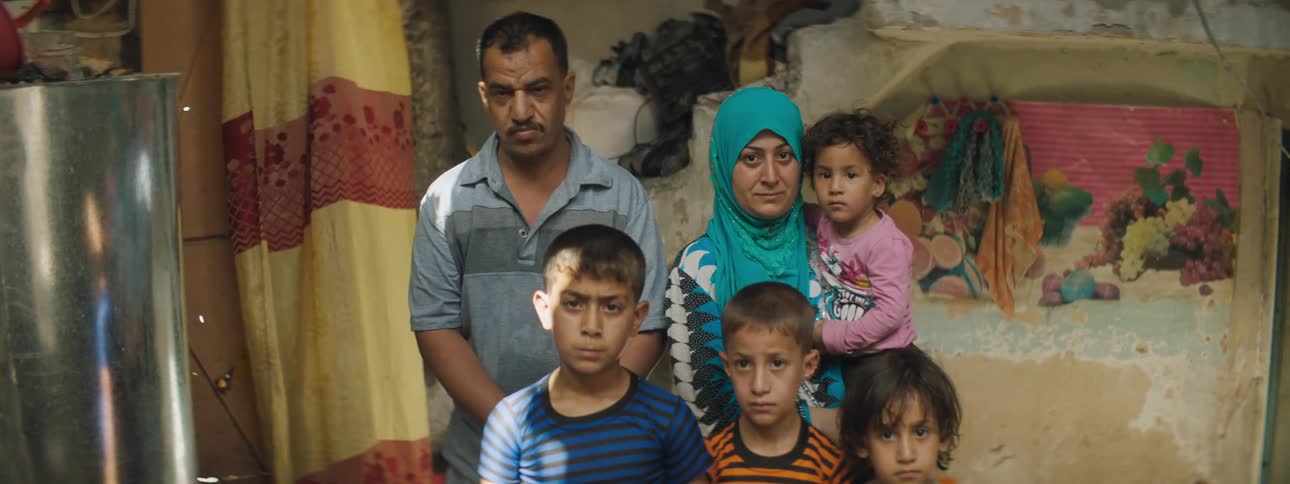 A family in a third world village stands in their shelter