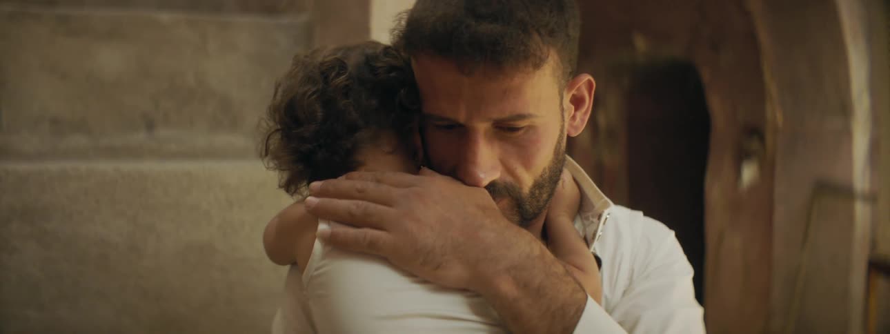 A man holding and hugging a baby with a doorway in the background