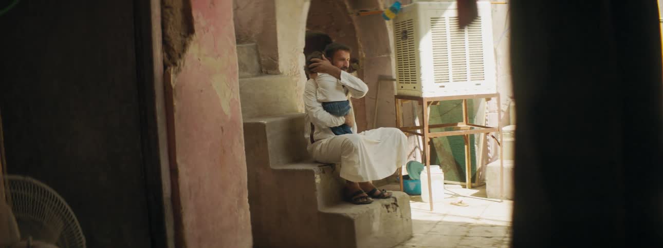 A father holds his baby and strokes their hair