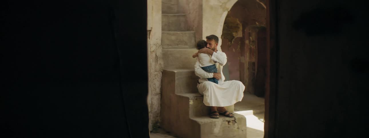 A young man hugs his baby and pats him on the back