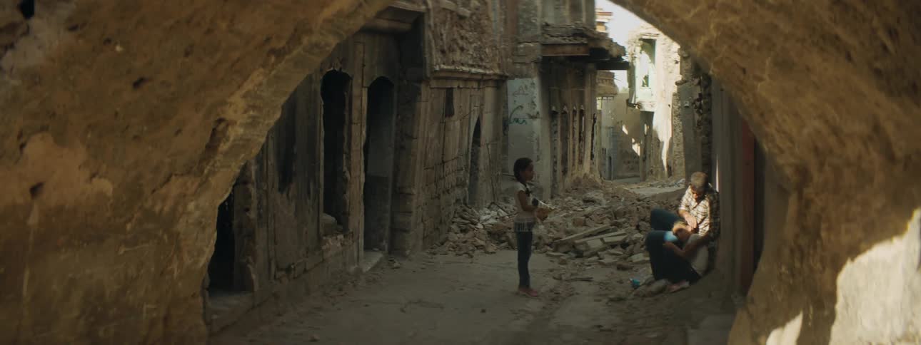 A man and two girls in an alley with rubble and debris