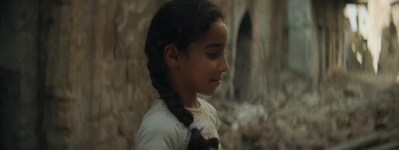 Girls share and eat snacks in an alley filled with rubble on a slum in a third world country