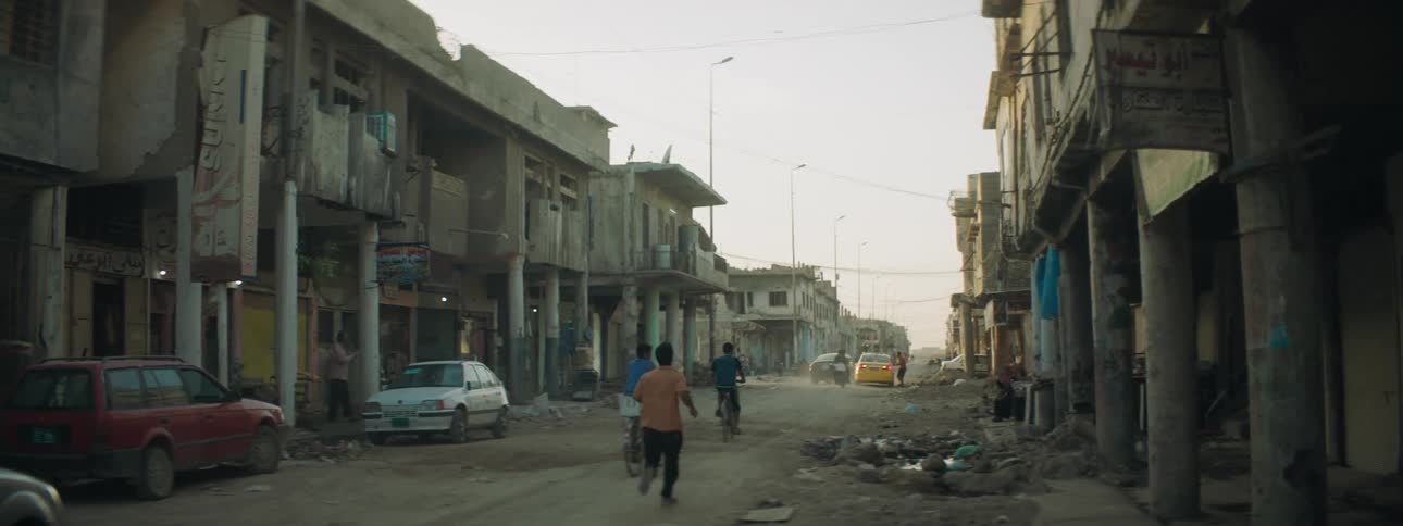 Pedestrians stands near car watching traffic move down damaged street
