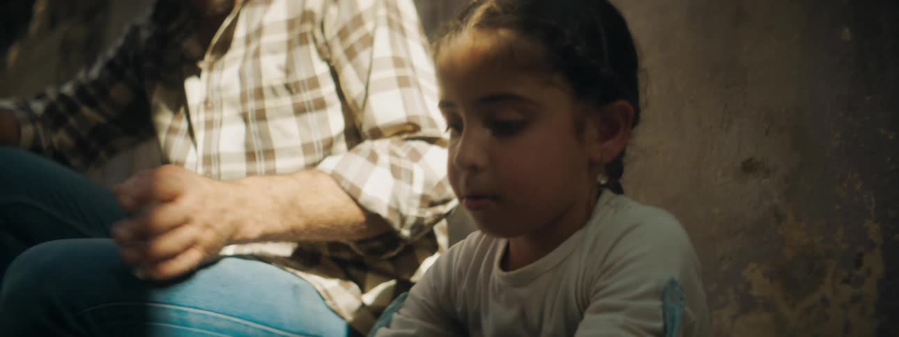 A man and a girl sitting with the girl eating chips
