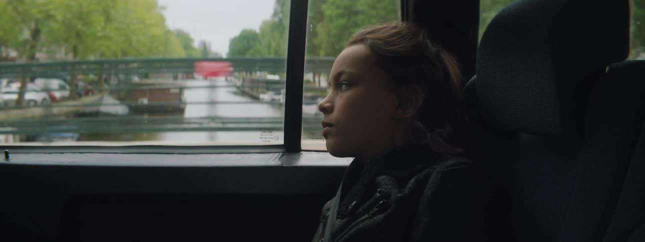 Girl looks out the side windows of a moving car in the city streets