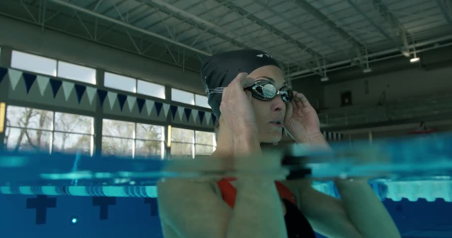 A woman adjusts her goggles in a pool