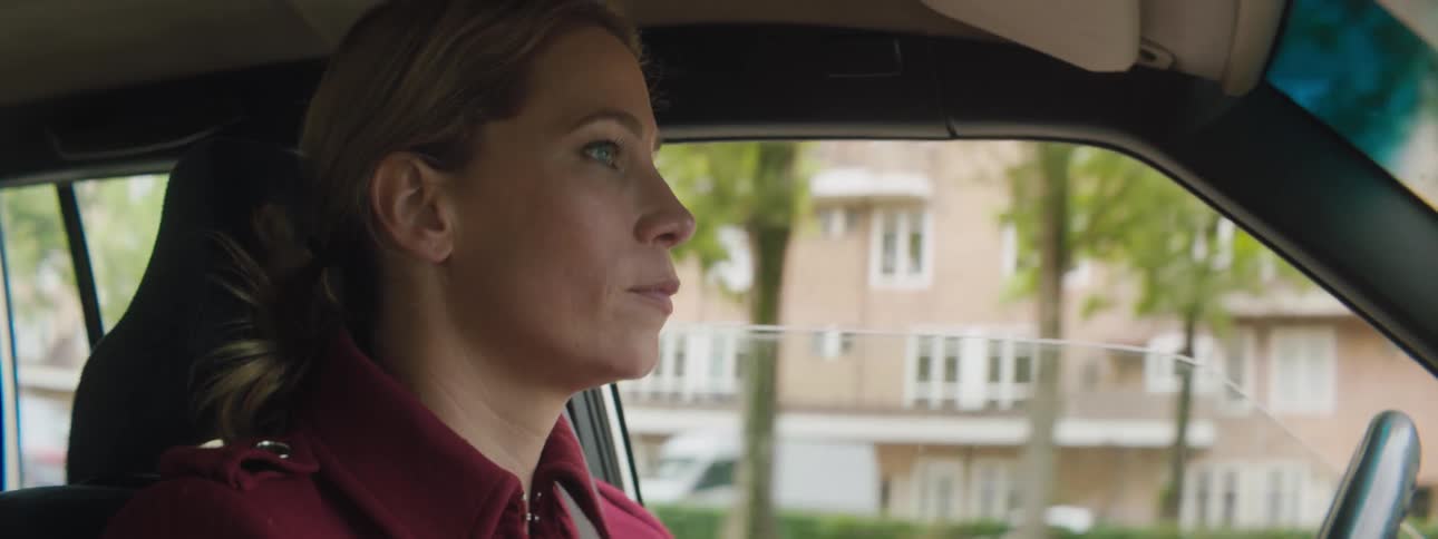 Side view of a blonde woman driving a car on a city road