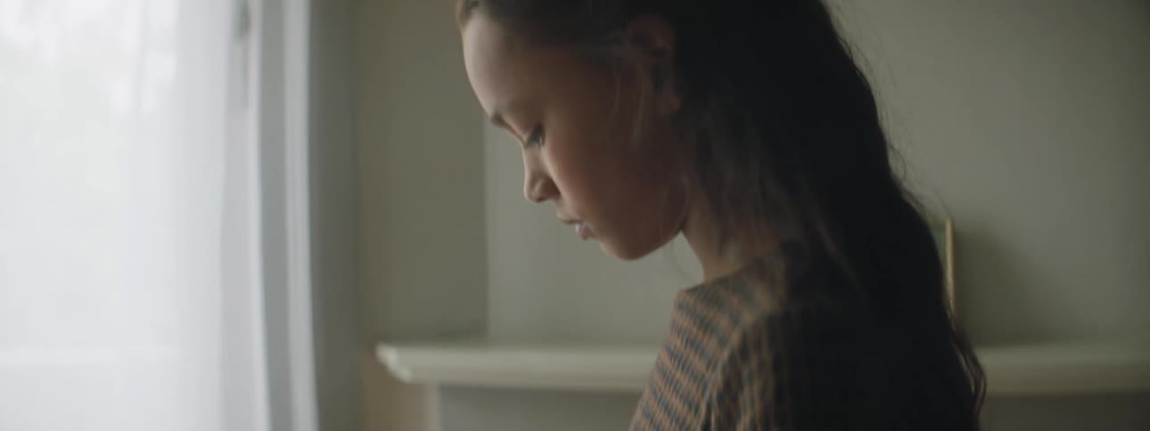A young girl at home looks at photograph of a man