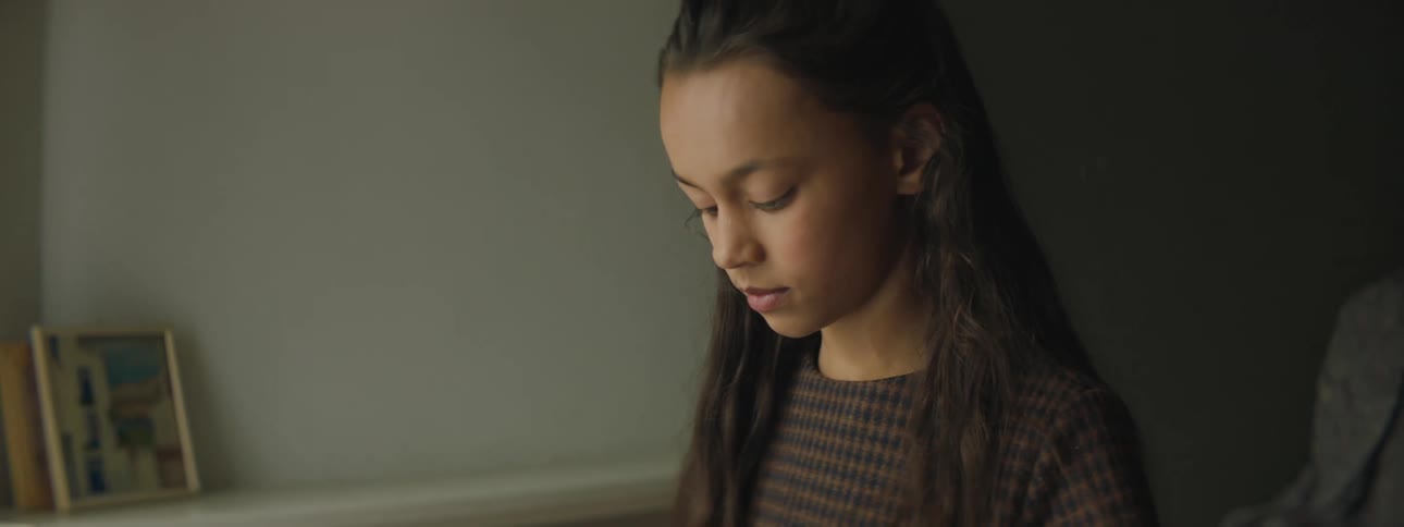 Girl with a sweatshirt and straight hair looks down in a room