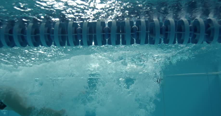A woman dives in a pool and swims