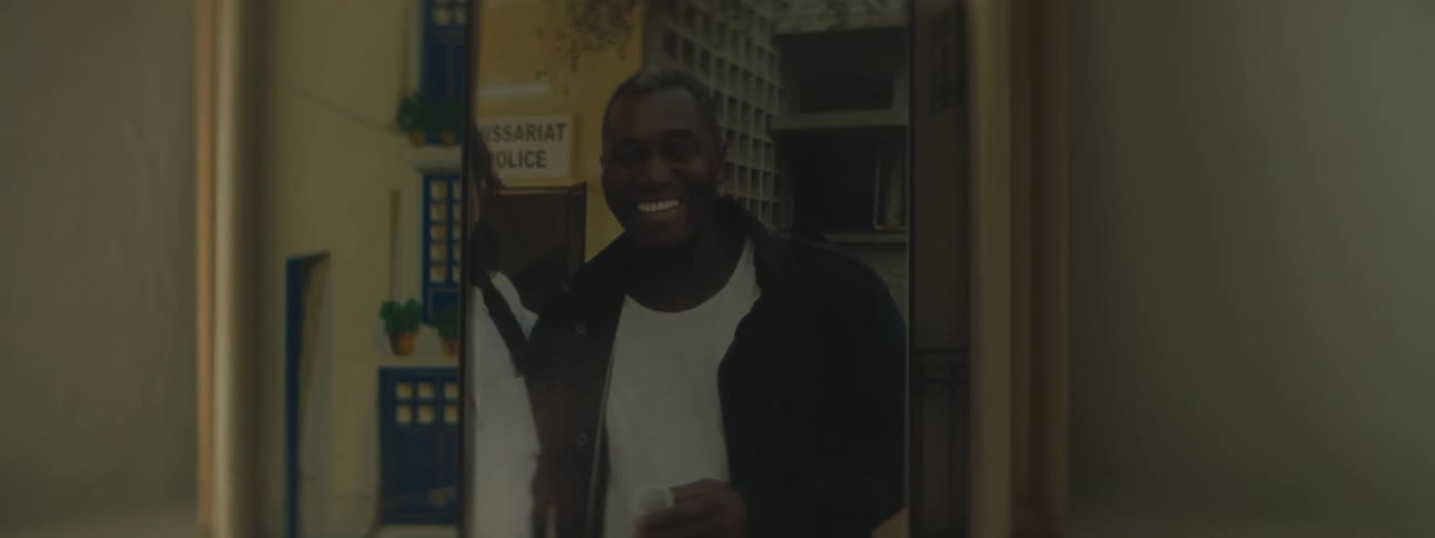 Framed picture of smiling man sits on white shelf against white wall
