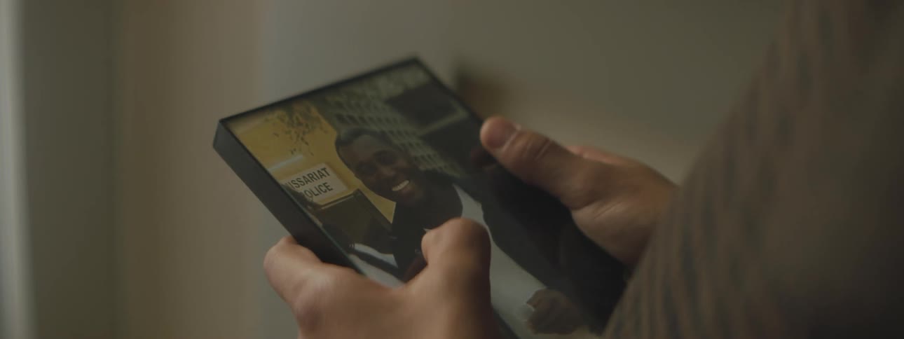 A child holding a framed photograph of a man