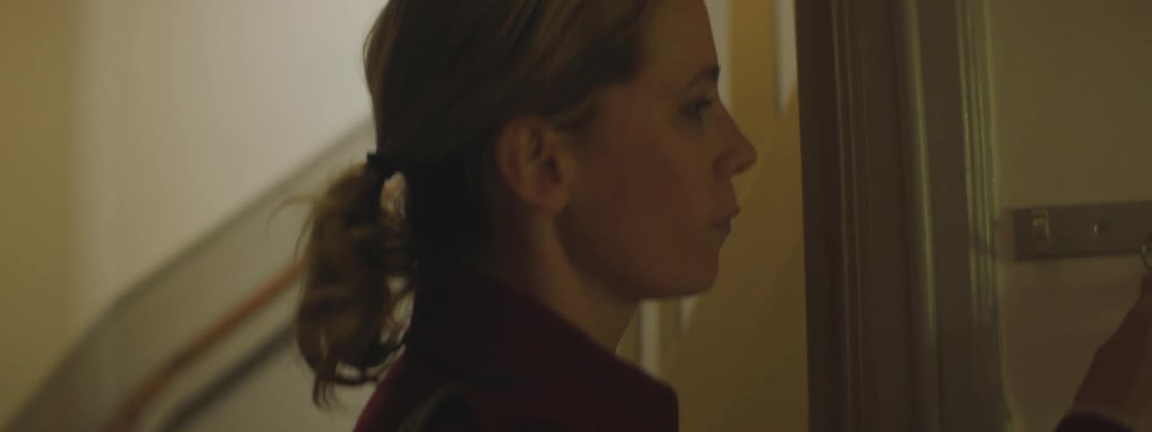 A woman hangs up a key and closes a door to her home