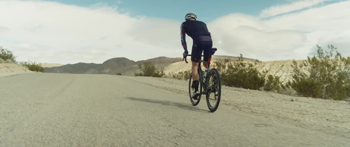 A man rides a bicycle on a rural dirt road